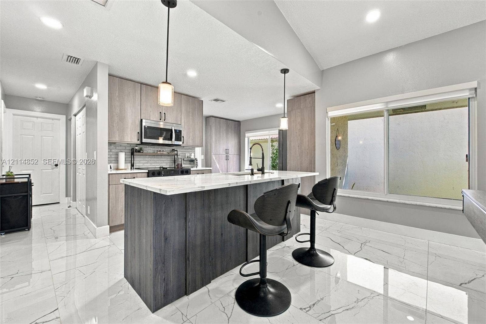 10780 NW 10th Street, Plantation, FL 33322 Kitchen featuring wood-finish cabinetry, a central island with a stone-top surface, large-format tile flooring, recessed lighting, and dual pendant light fixtures