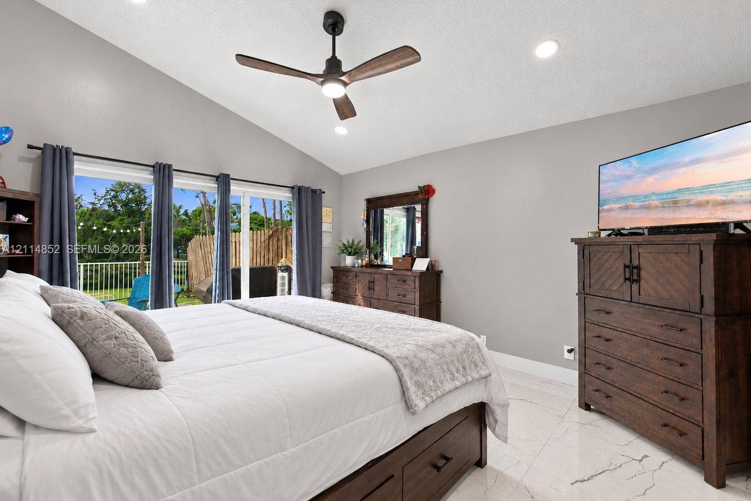 10780 NW 10th Street, Plantation, FL 33322 Vaulted ceiling with a matte black modern ceiling fan, large glass sliding doors, and polished stone-finish flooring