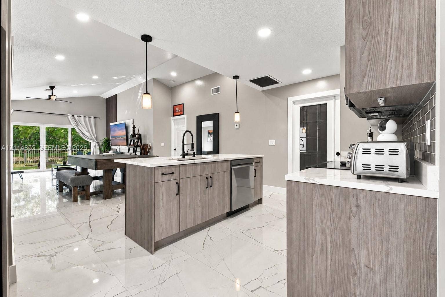 10780 NW 10th Street, Plantation, FL 33322 Kitchen featuring wood-finish cabinetry, stone-style countertops, recessed ceiling lighting, pendant light fixtures, and large-format tile flooring