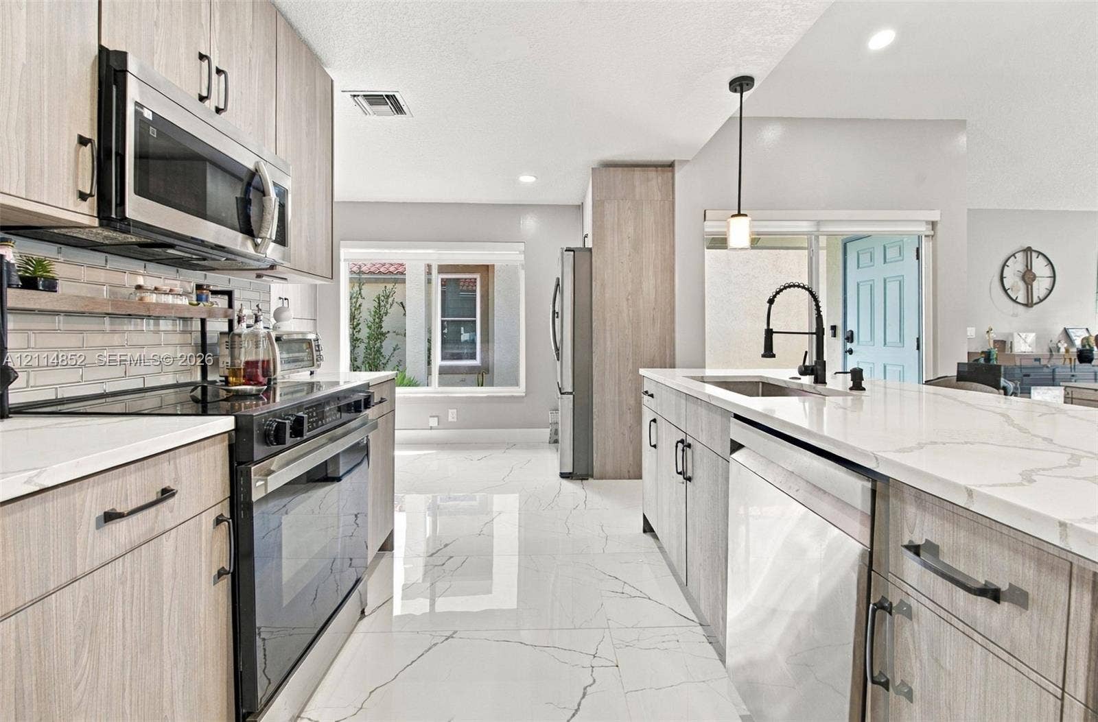 10780 NW 10th Street, Plantation, FL 33322 Kitchen featuring wood-finish cabinetry, stone-surface countertops with waterfall edge, large-format tile flooring, stainless steel appliances, and a matte black gooseneck faucet