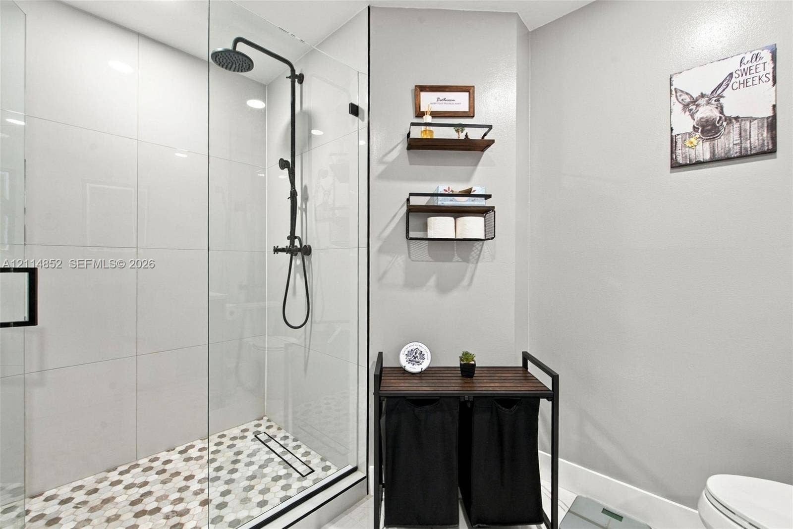 10780 NW 10th Street, Plantation, FL 33322 Walk-in shower featuring a frameless glass enclosure, matte black rainfall showerhead, and hexagonal mosaic floor tile