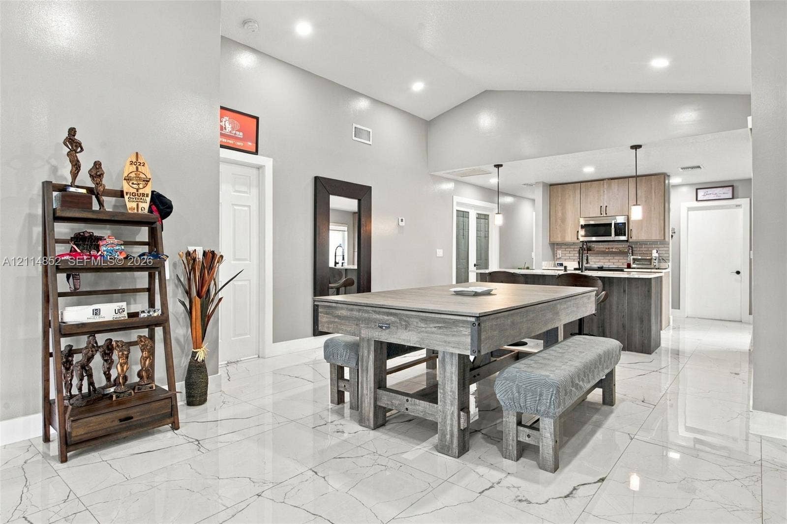 10780 NW 10th Street, Plantation, FL 33322 Open-concept interior featuring vaulted ceilings, polished tile flooring with marble-style veining, recessed lighting, and a kitchen equipped with two-tone cabinetry and stainless-steel appliances