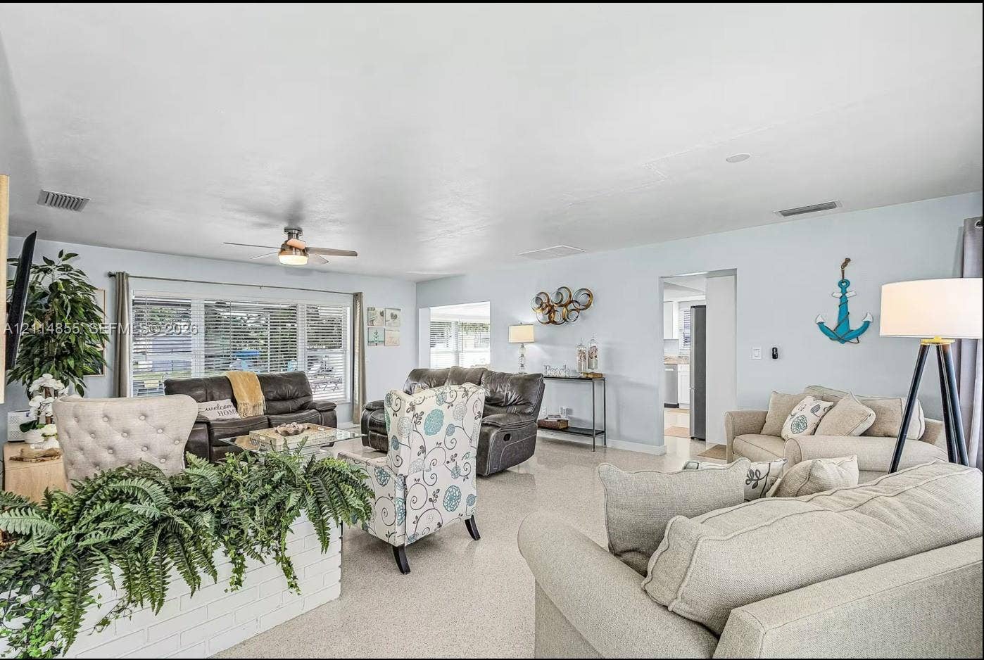 802 Montclair Court, Cape Coral, FL 33904 Living area featuring large windows, neutral stone-finish flooring, and a ceiling fan with integrated lighting