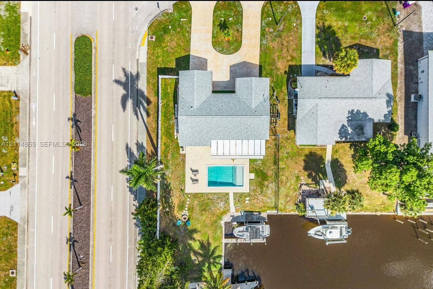 802 Montclair Court, Cape Coral, FL 33904 Aerial perspective featuring a waterfront property with a private swimming pool, paved driveway, and dedicated boat slip