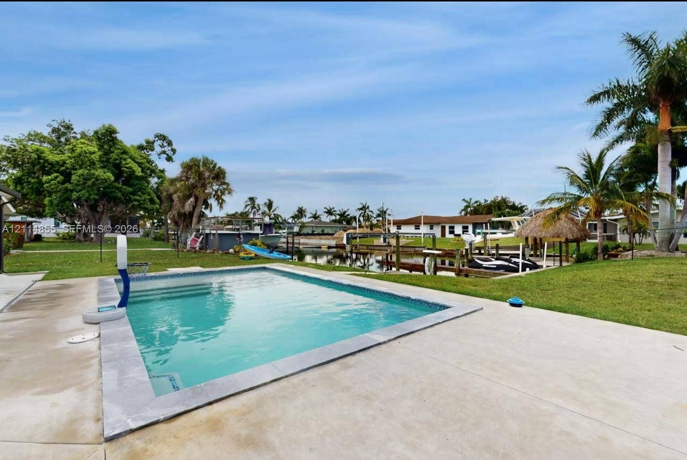 802 Montclair Court, Cape Coral, FL 33904 In-ground swimming pool with concrete decking, private dock, and mature palm trees situated on a waterfront lot