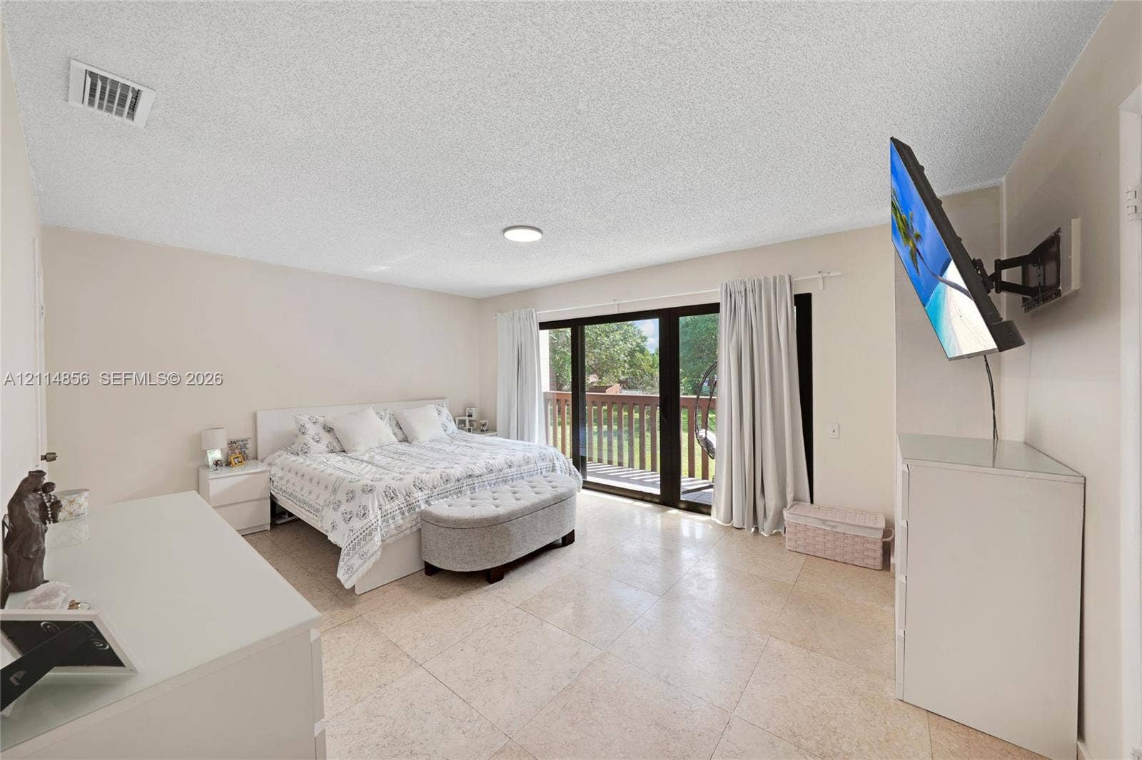Miami, FL 33173 Neutral-toned room featuring large-format tile flooring, sliding glass doors, and a balcony with wood-finish railings