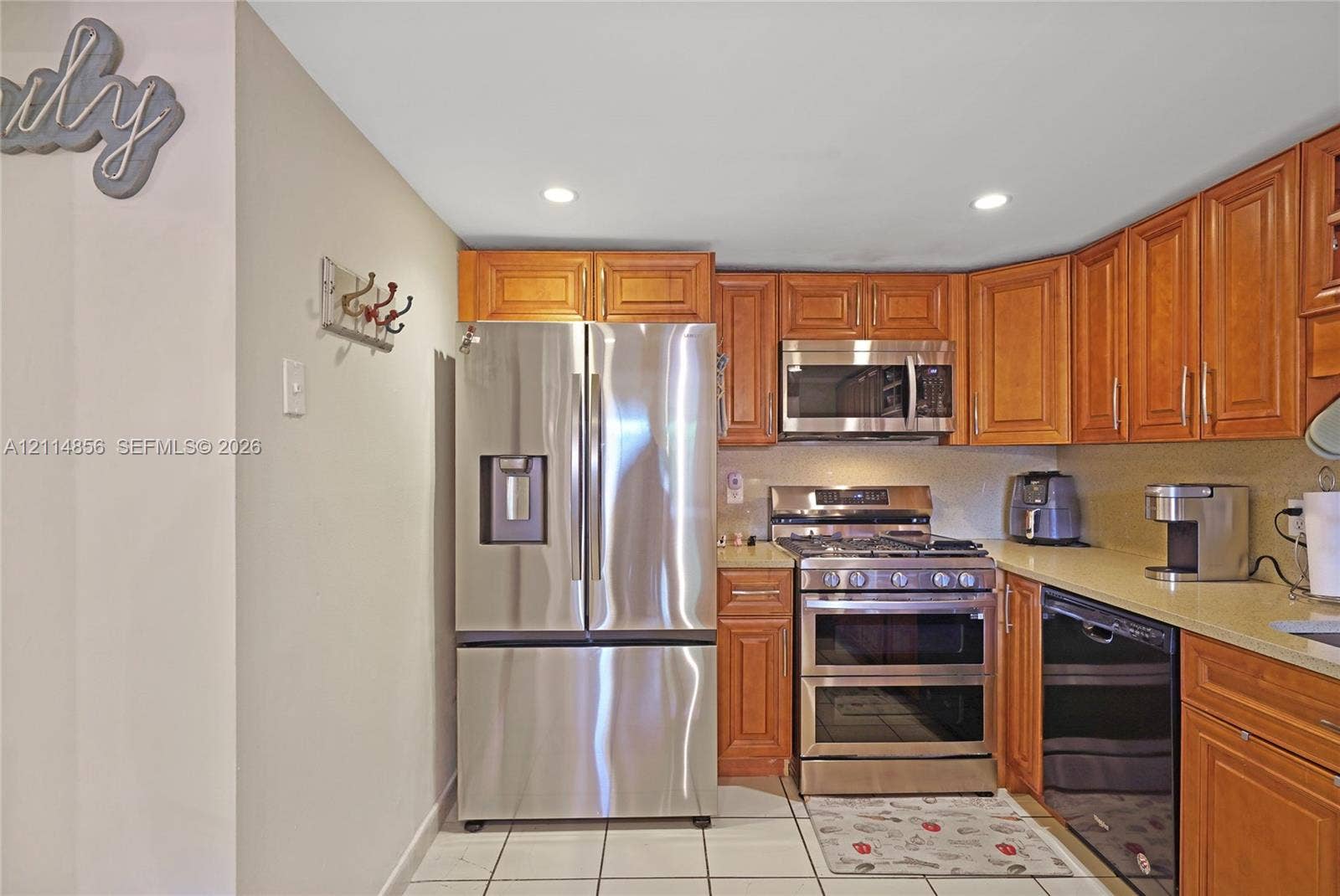Miami, FL 33173 Kitchen featuring natural wood cabinetry, stainless steel appliances, solid surface countertops, recessed lighting, and tile flooring