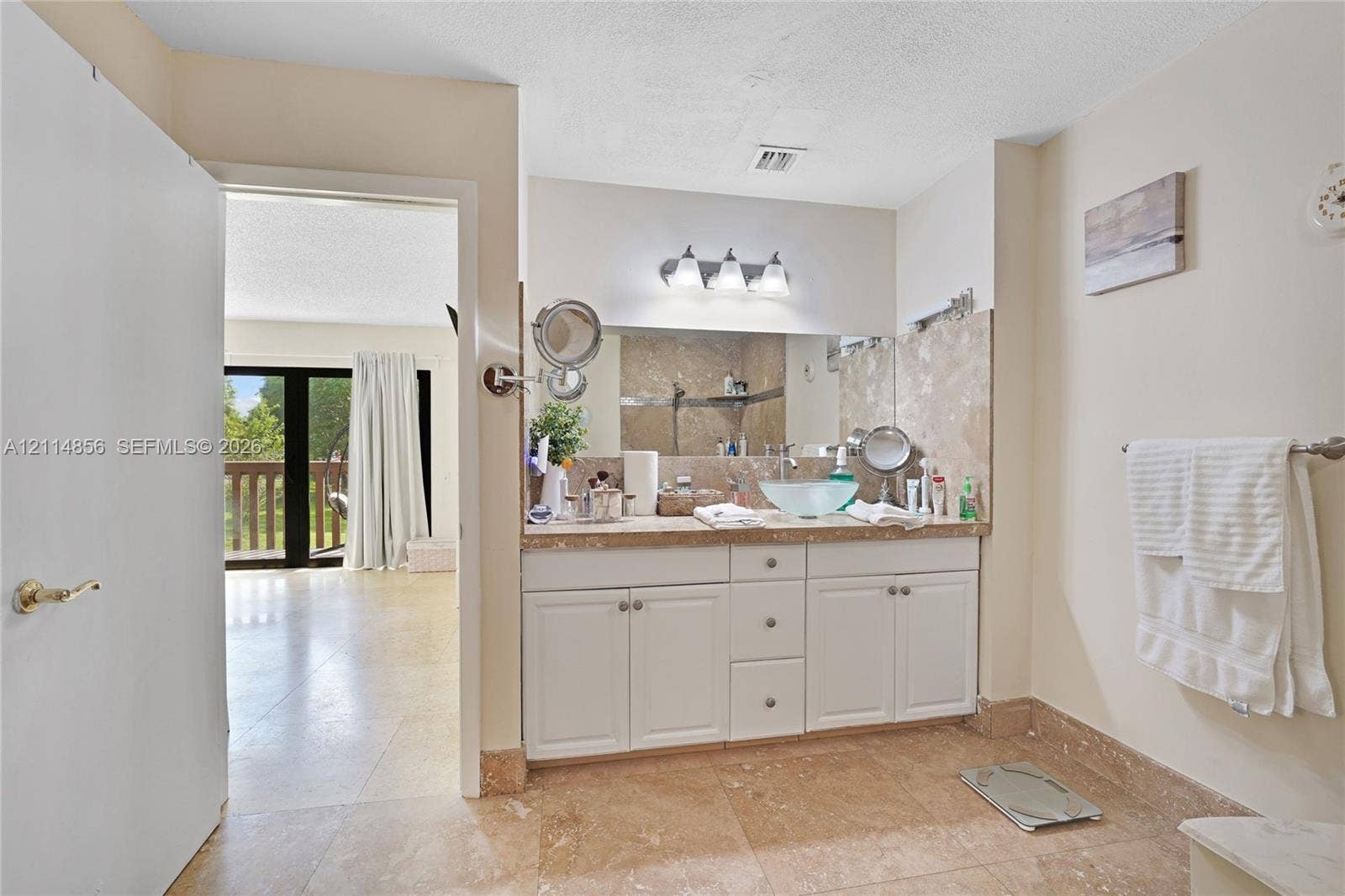 Miami, FL 33173 Bathroom featuring a vanity with white cabinetry, a glass vessel sink, stone-finish countertop, full-width mirror, and three-light fixture
