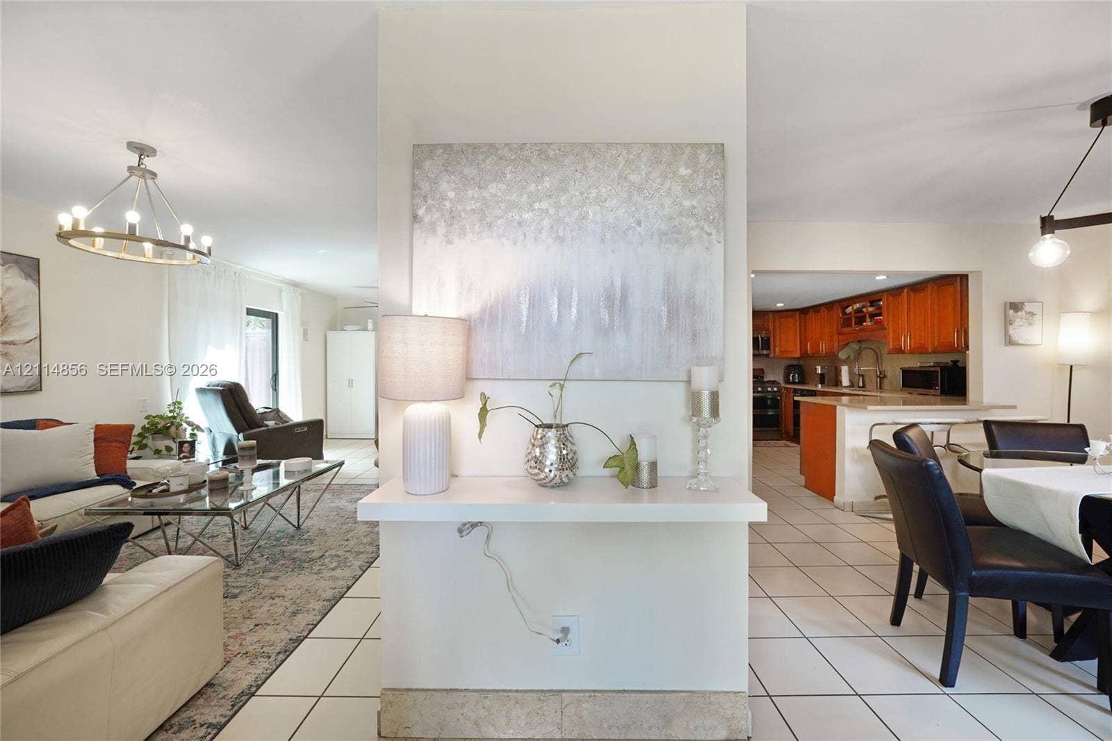Miami, FL 33173 Open-concept interior featuring large-format tile flooring, central partition wall with built-in display shelf, and chandelier lighting