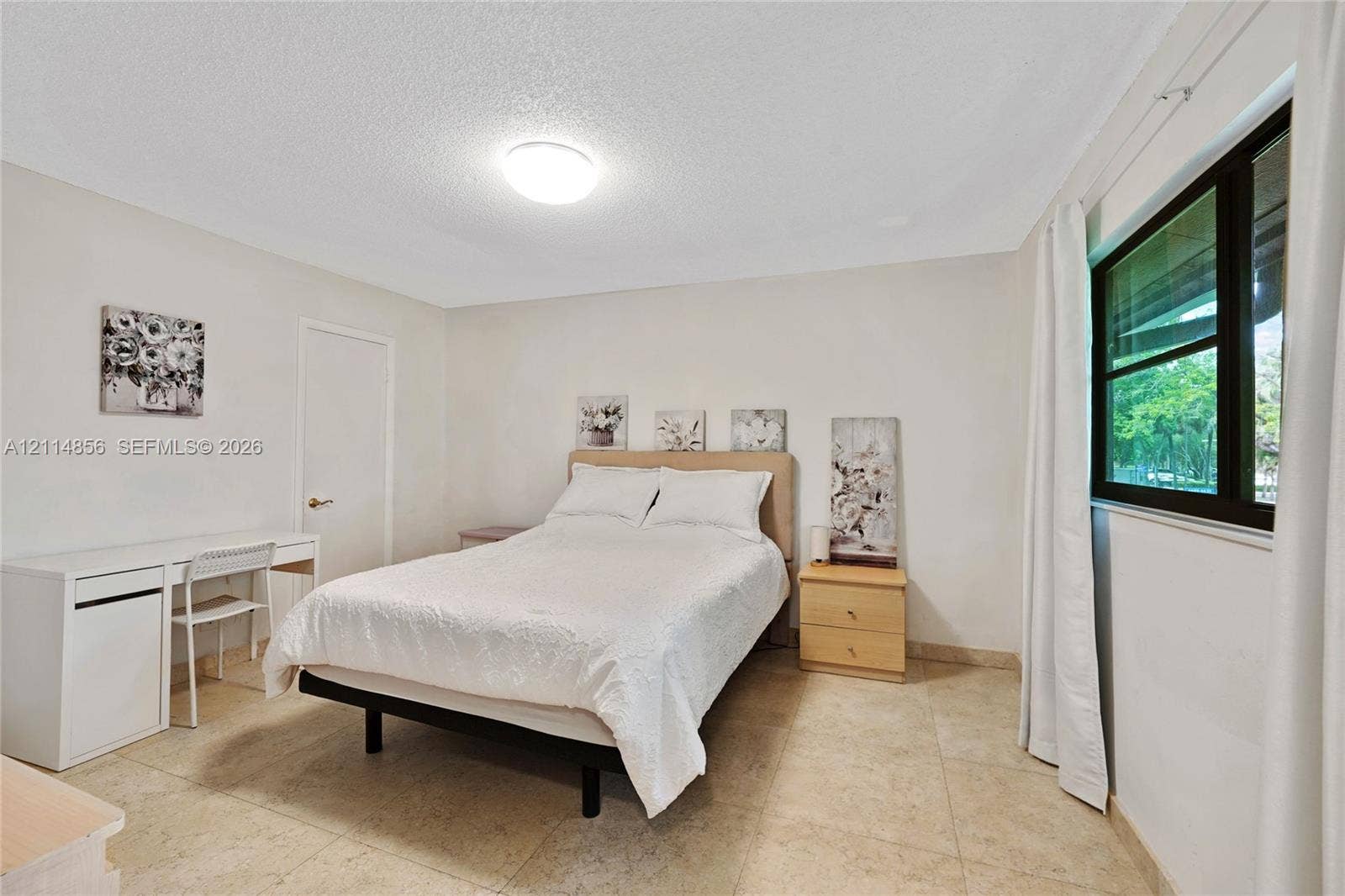 Miami, FL 33173 Neutral-toned room featuring stone-finish tile flooring, a large window with black framing, and a central flush-mount ceiling light