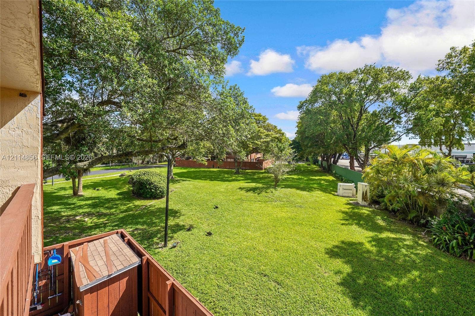 Miami, FL 33173 Expansive backyard featuring a manicured lawn, mature trees, and wooden fencing