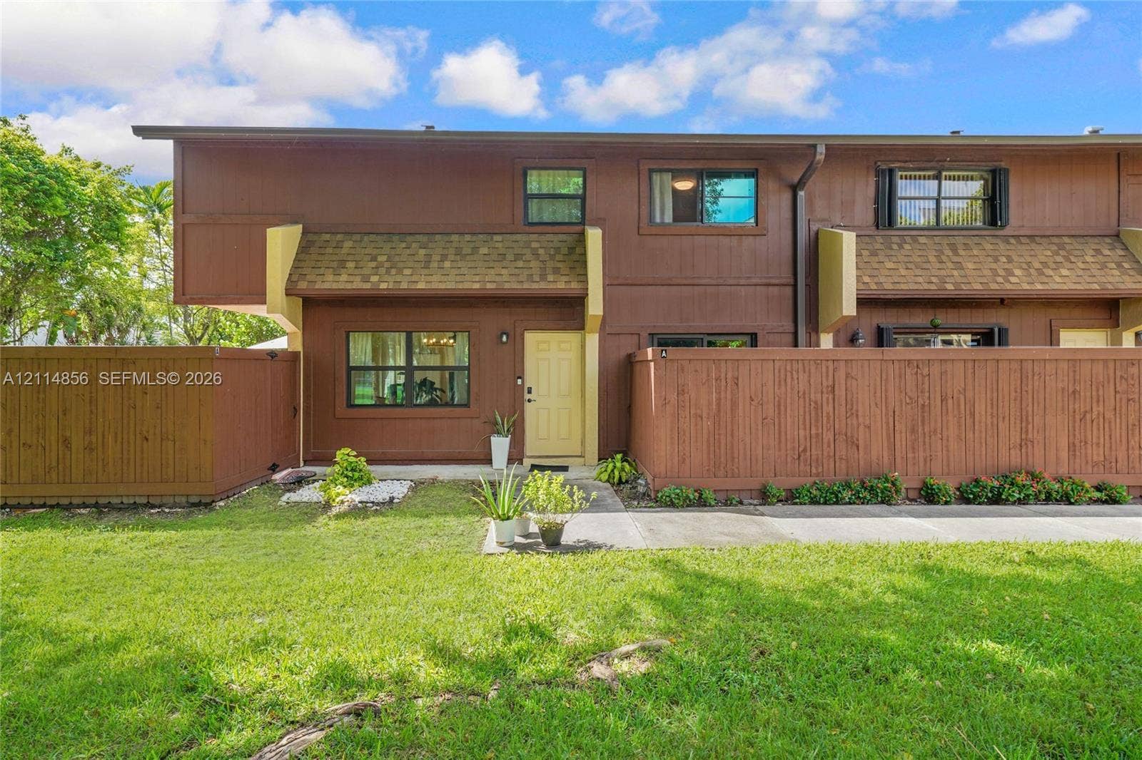 Miami, FL 33173 Two-story exterior featuring wood-paneled siding, shingle-style roof accents, horizontal wood privacy fencing, and multi-pane windows