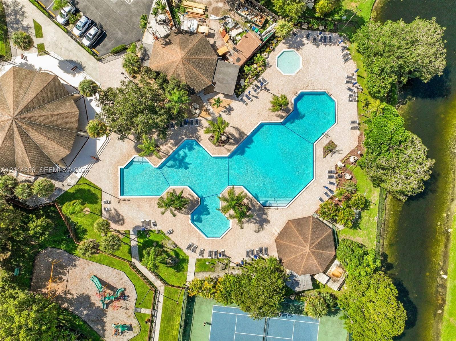 Miami, FL 33173 Large-scale community swimming pool, separate spa, hardscaped patio surround, tennis court, and playground area