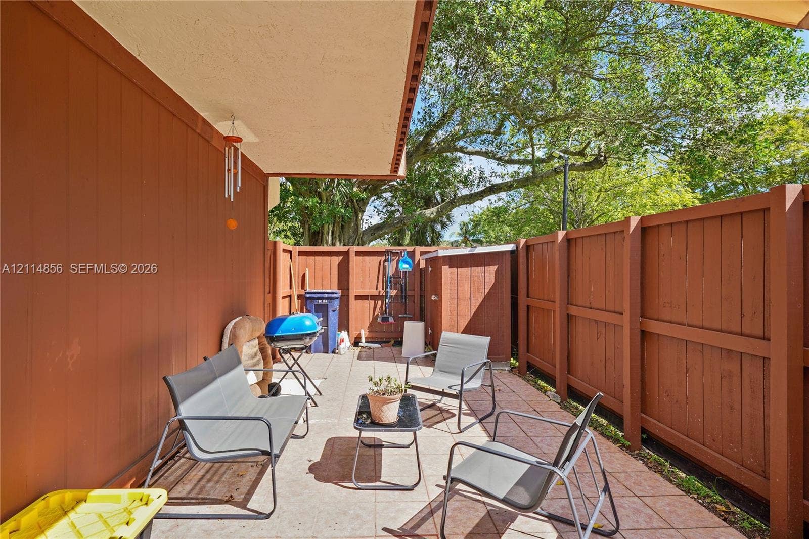 Miami, FL 33173 Covered patio featuring ceramic tile flooring, solid wood-panel fencing, and a built-in outdoor storage unit
