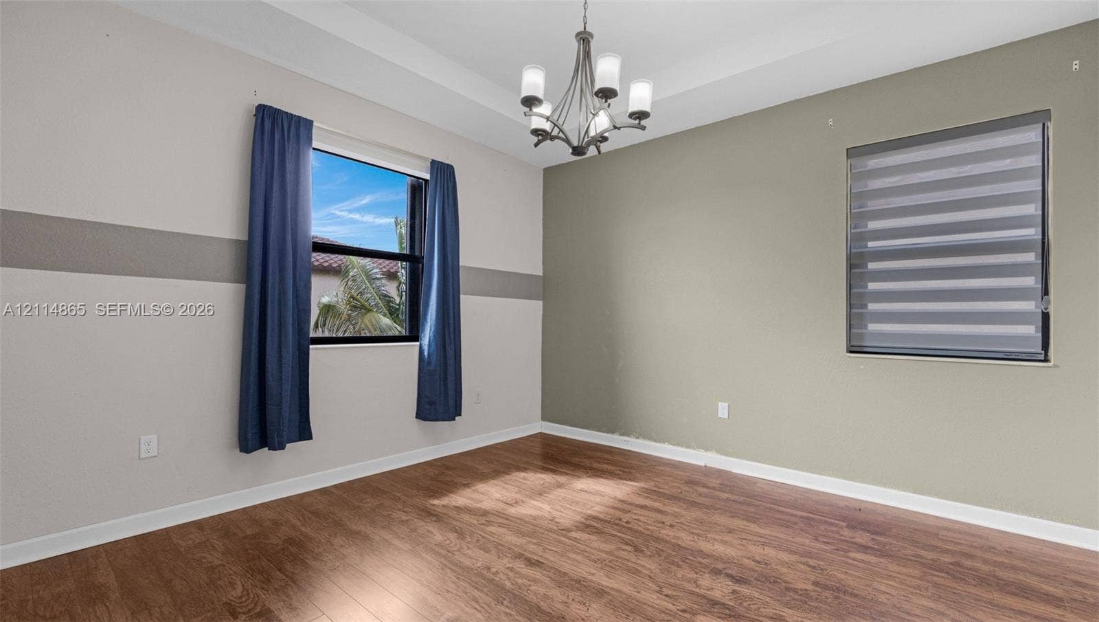 3754 NE 2nd Street, Homestead, FL 33033 Tray ceiling featuring a multi-arm chandelier, wood-finish flooring, and horizontal window treatments