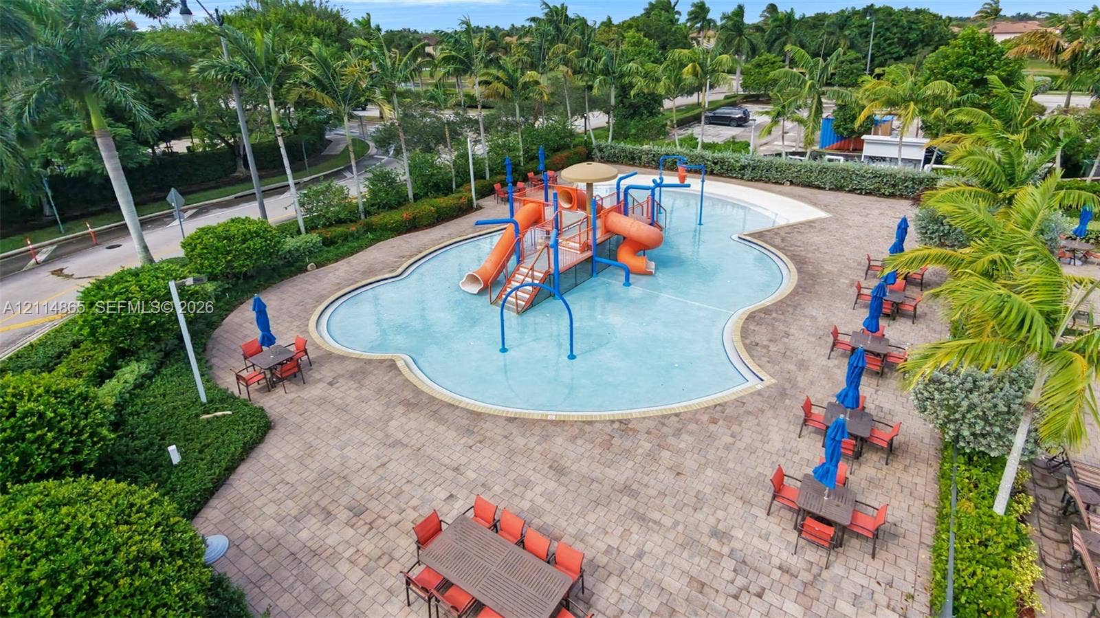 3754 NE 2nd Street, Homestead, FL 33033 Community pool area featuring a water slide, integrated splash pad, paver patio, and mature palm landscaping