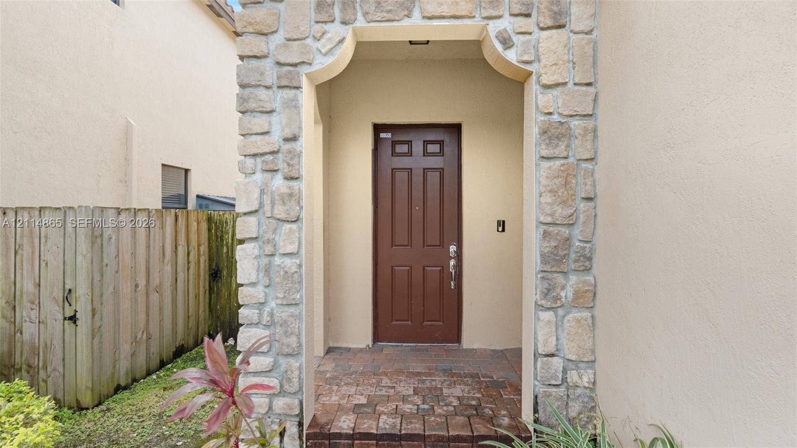 3754 NE 2nd Street, Homestead, FL 33033 Entryway featuring a stone-clad arched portico, paver flooring, and a six-panel door
