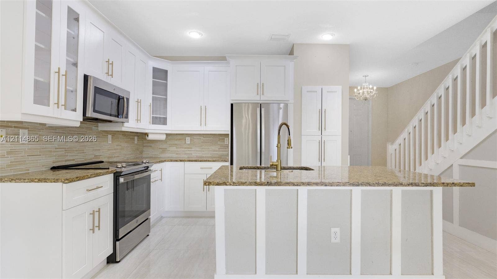 3754 NE 2nd Street, Homestead, FL 33033 Kitchen featuring white shaker-style cabinetry, a central island with a stone countertop, a linear tile backsplash, stainless steel appliances, and wood-finish flooring