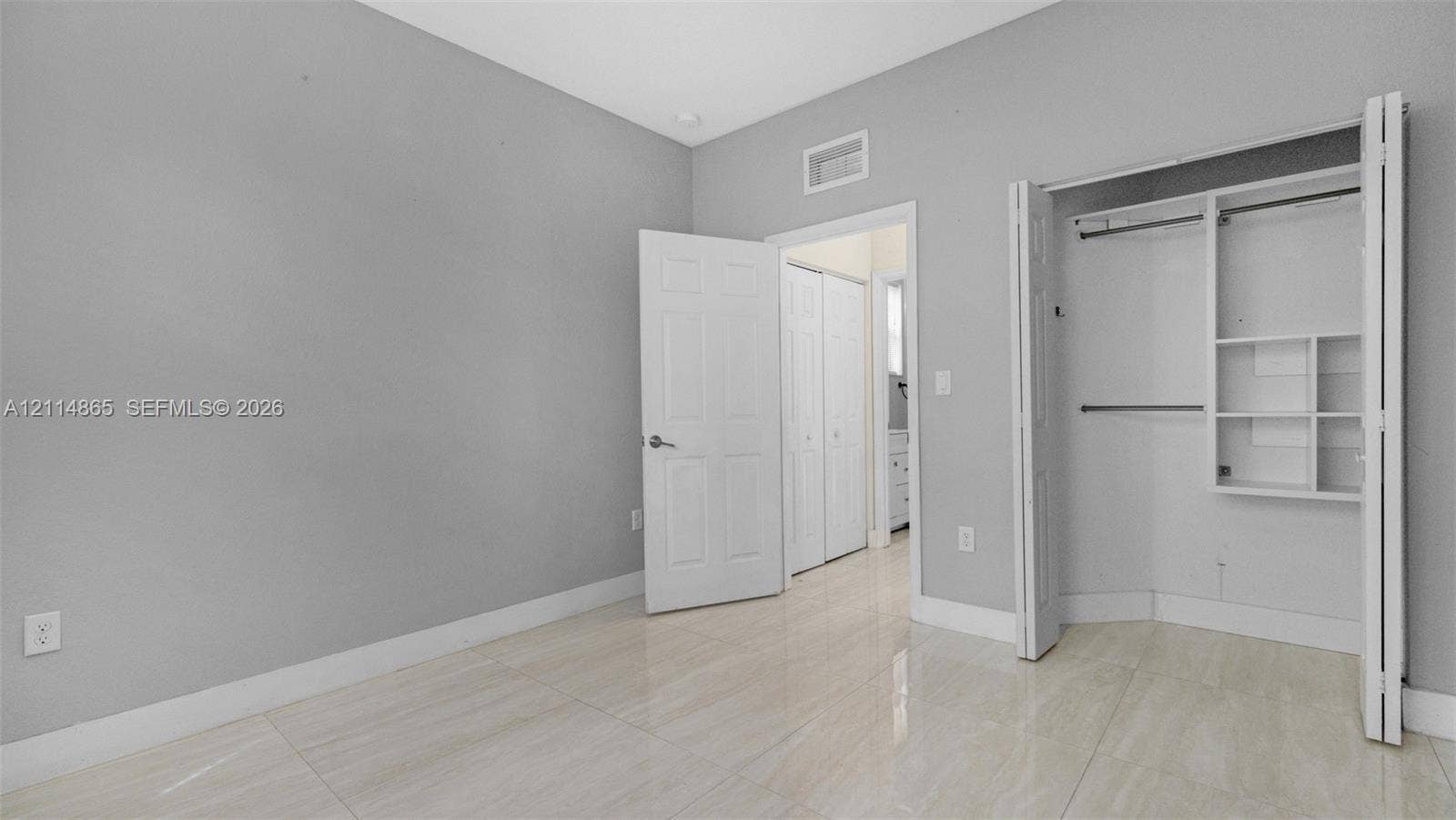 3754 NE 2nd Street, Homestead, FL 33033 1st floor bedroom! Perfect guest/in-law space Interior space featuring neutral wall paint, polished tile flooring, and a walk-in closet with built-in shelving