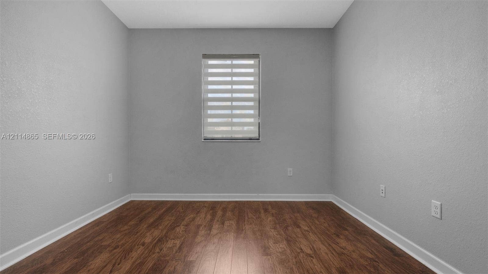 3754 NE 2nd Street, Homestead, FL 33033 Neutral-toned walls featuring wood-finish flooring and a window fitted with adjustable light-filtering blinds