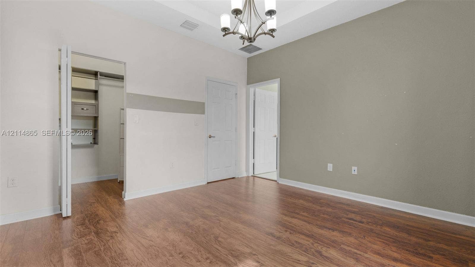 3754 NE 2nd Street, Homestead, FL 33033 Room featuring wood-finish flooring, tray ceiling, multi-arm chandelier, and built-in closet shelving