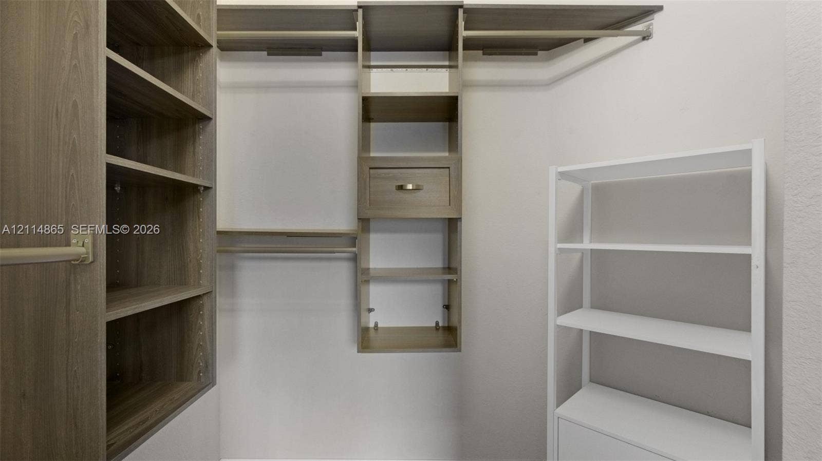 3754 NE 2nd Street, Homestead, FL 33033 Custom closet organization system featuring wood-finish shelving, integrated clothing rods, and a central drawer unit with metallic hardware