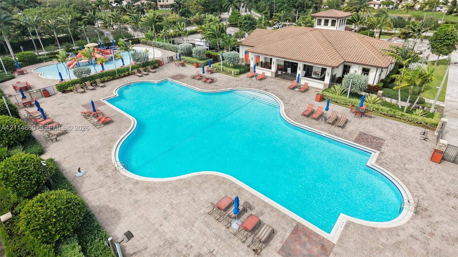 3754 NE 2nd Street, Homestead, FL 33033 Community amenities featuring a large swimming pool with paver decking, a secondary splash pool with play structures, and a clubhouse with a multi-hipped roof