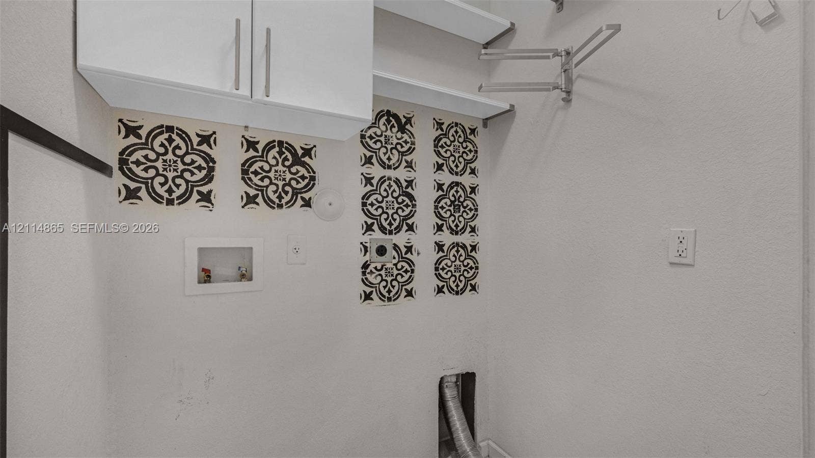 3754 NE 2nd Street, Homestead, FL 33033 Utility area featuring white overhead cabinetry, open shelving, decorative tile accents, and a retractable wall-mounted garment rack