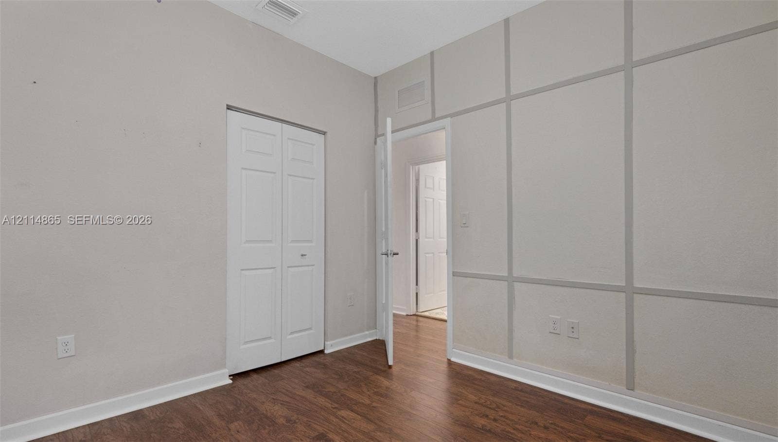 3754 NE 2nd Street, Homestead, FL 33033 Room featuring wood-finish flooring, decorative wall molding, and a bi-fold closet door