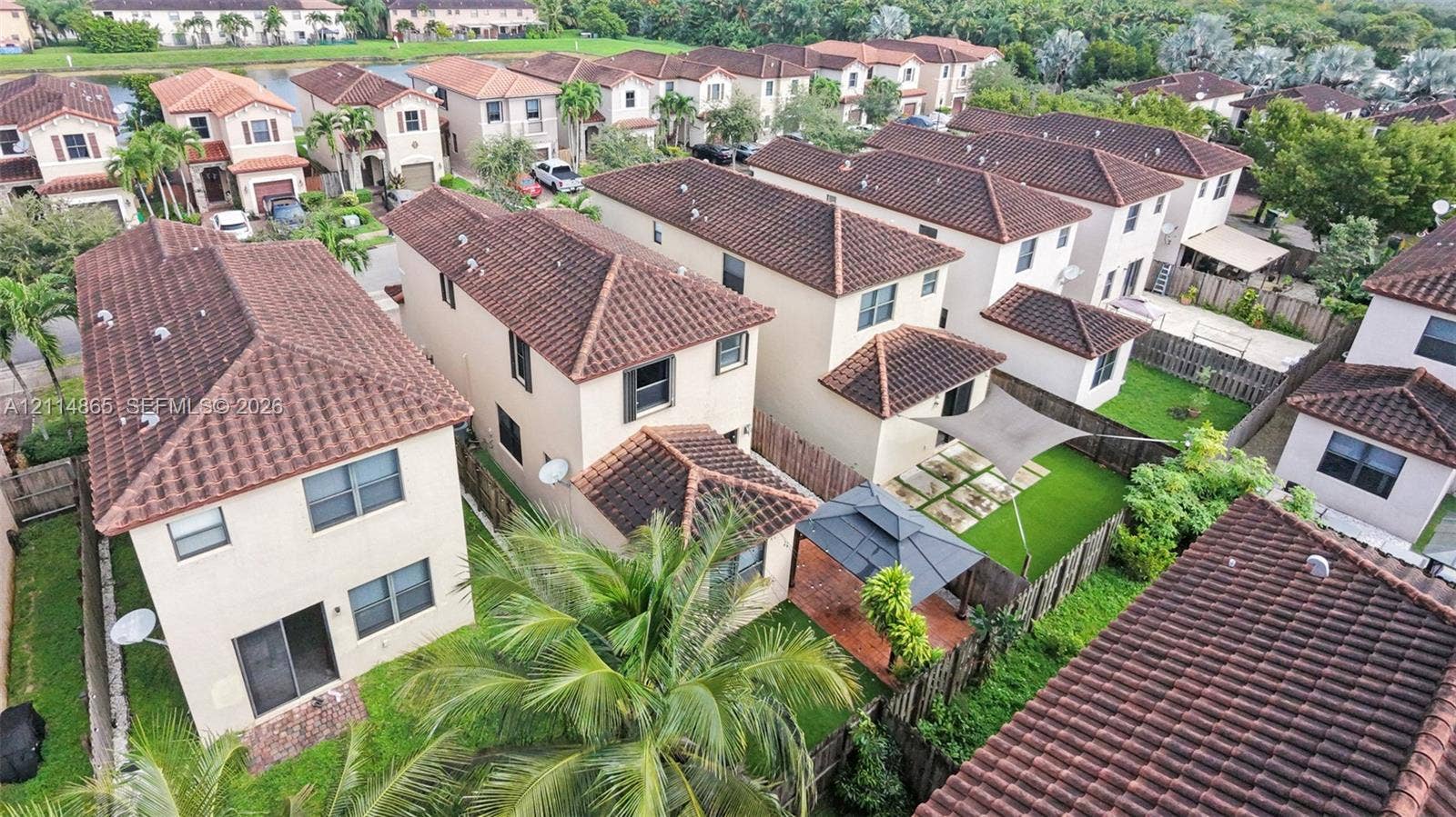 3754 NE 2nd Street, Homestead, FL 33033 Aerial perspective of a multi-story residential community featuring tile roofs, stucco exteriors, and fenced backyards
