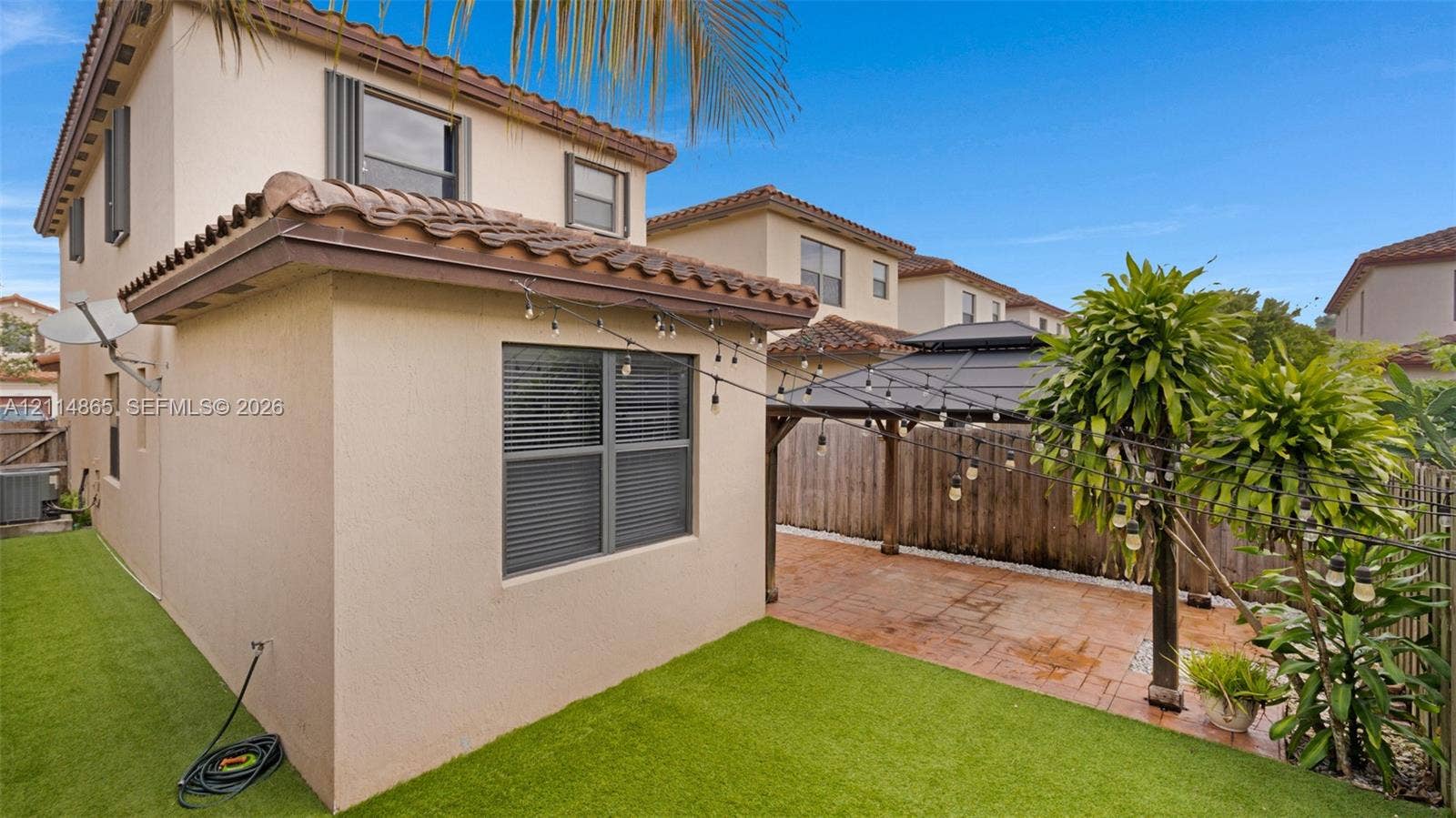 3754 NE 2nd Street, Homestead, FL 33033 Stucco exterior with a tile roof, paved patio area, and synthetic turf lawn