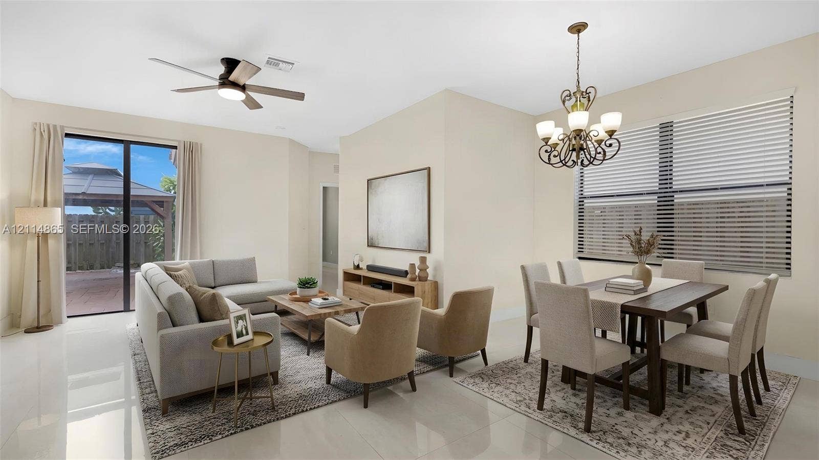 3754 NE 2nd Street, Homestead, FL 33033 Virtually staged. Open-concept floor plan featuring light-toned flooring, an ornate multi-arm chandelier, a ceiling fan with integrated lighting, and glass sliding doors