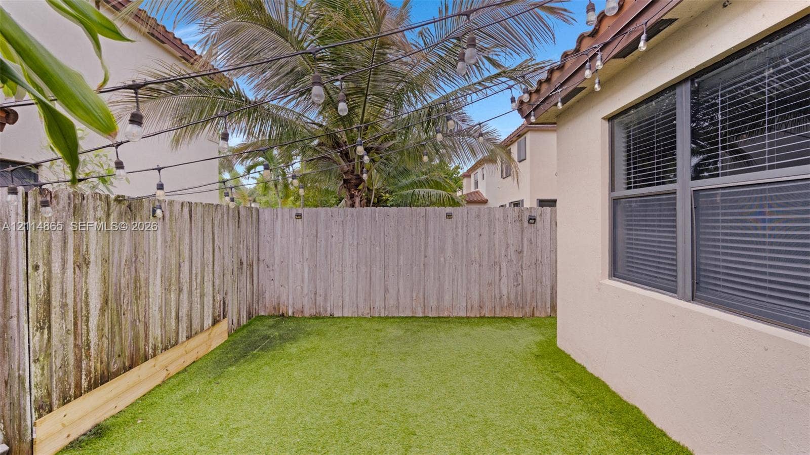 3754 NE 2nd Street, Homestead, FL 33033 Outdoor space featuring artificial turf, wood fencing, and overhead string lighting