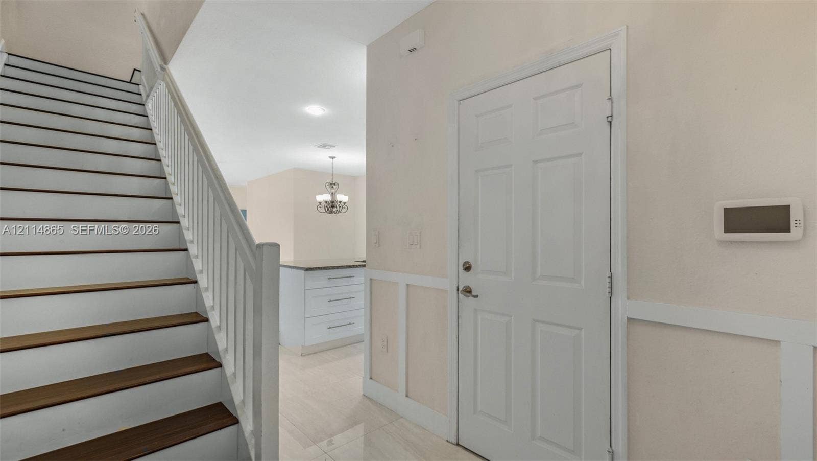3754 NE 2nd Street, Homestead, FL 33033 Interior entry featuring a staircase with wood-finish treads and white balusters, wainscoting wall paneling, and tile flooring