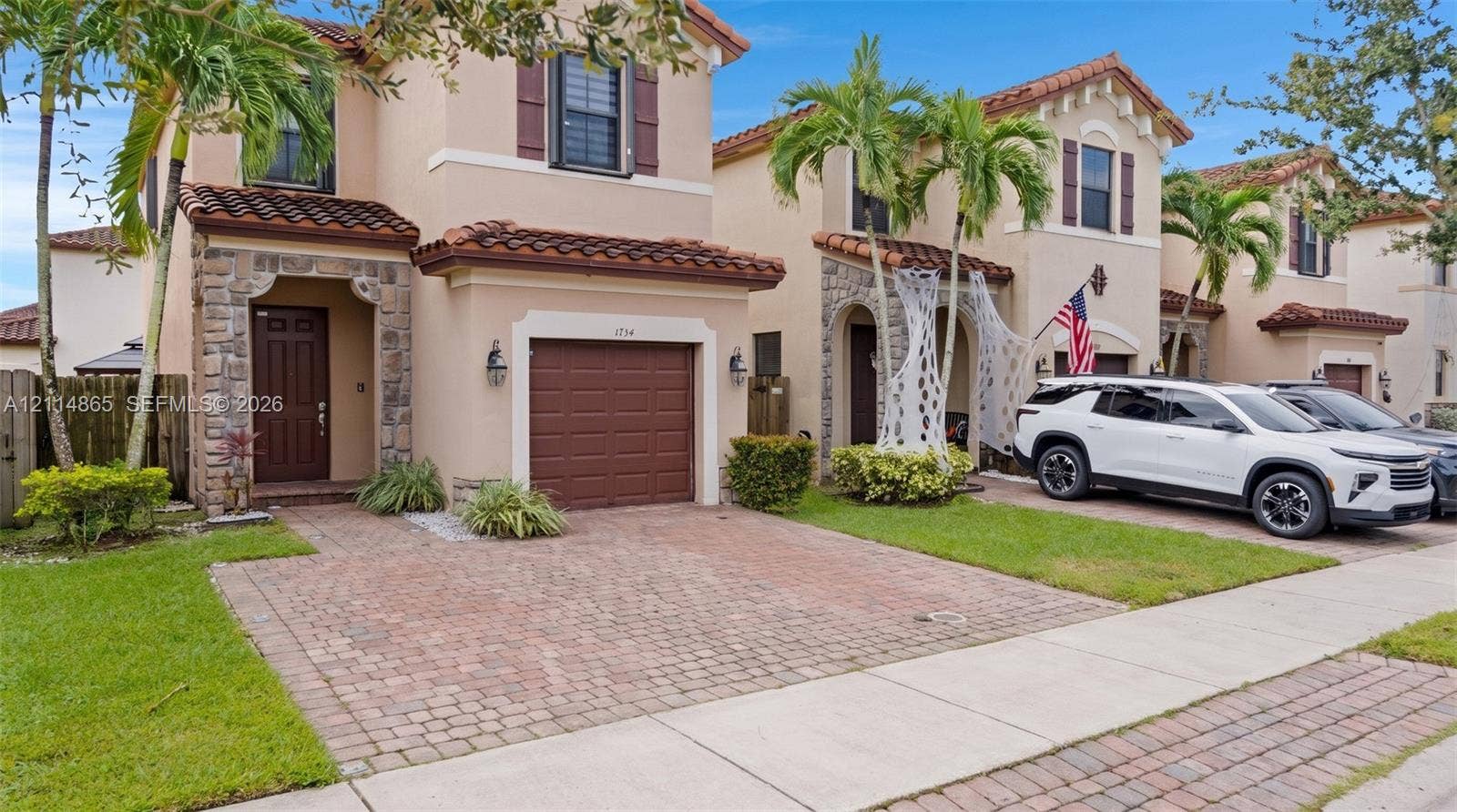 3754 NE 2nd Street, Homestead, FL 33033 Two-story exterior featuring stucco siding, stone veneer accents, multi-tonal brick paver driveway, and a clay tile roof