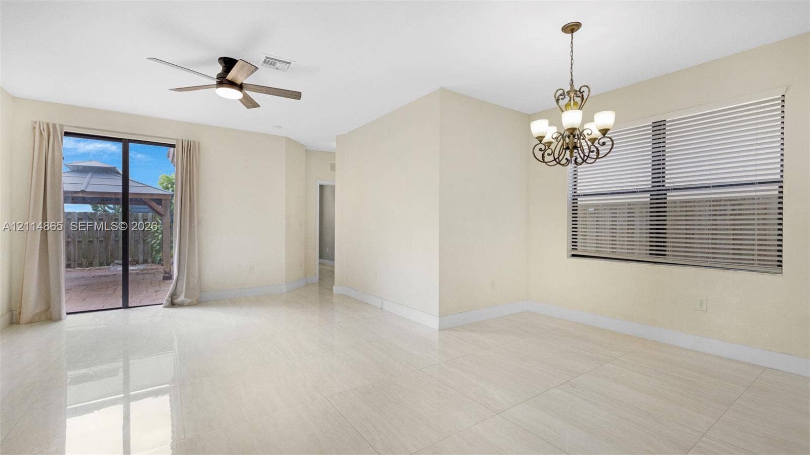 3754 NE 2nd Street, Homestead, FL 33033 Open-concept interior featuring large-format tile flooring, a multi-arm chandelier, ceiling fan with integrated lighting, and glass sliding doors