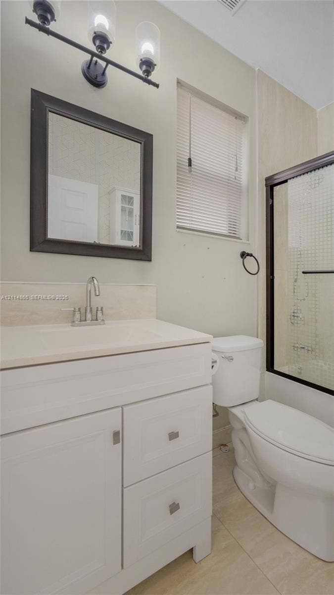 3754 NE 2nd Street, Homestead, FL 33033 1st floor bathroom! Perfect guest bath/in-law space White vanity cabinet with a stone-surface countertop, rectangular framed wall mirror, three-light vanity fixture, and shower enclosure with a dark-finish frame