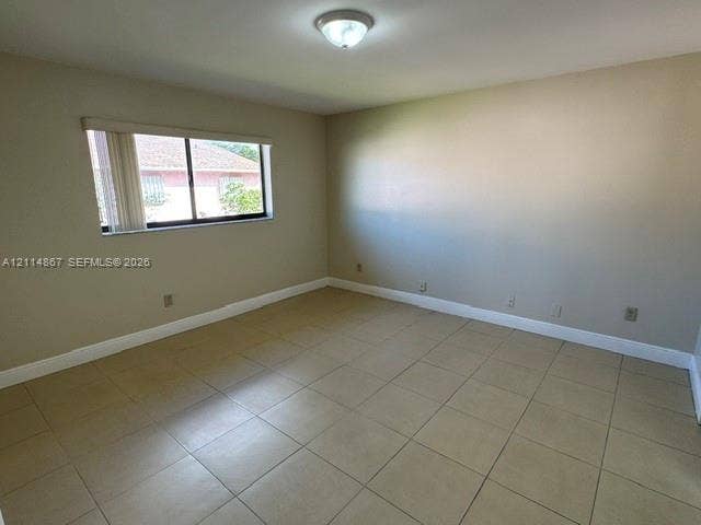 1663 W 41st Street, #1663, Hialeah, Hialeah, FL 33012 Neutral-toned room featuring large-format ceramic floor tile, a ceiling-mounted light fixture, and a single-pane window with vertical blinds