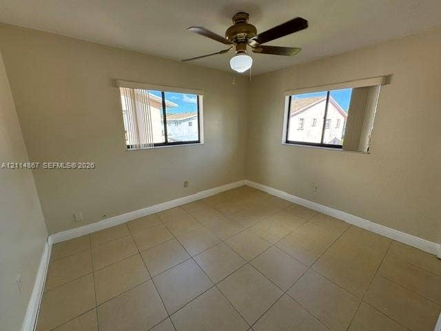 1663 W 41st Street, #1663, Hialeah, Hialeah, FL 33012 Neutral wall-toned room featuring large-format tile flooring, dual-aspect windows with horizontal blinds, and a central ceiling fan with an integrated light fixture