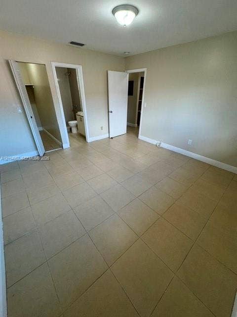 1663 W 41st Street, #1663, Hialeah, Hialeah, FL 33012 Neutral-toned interior space featuring large-format tile flooring, a flush-mount ceiling light fixture, and multiple access points including a walk-in closet and internal doorway