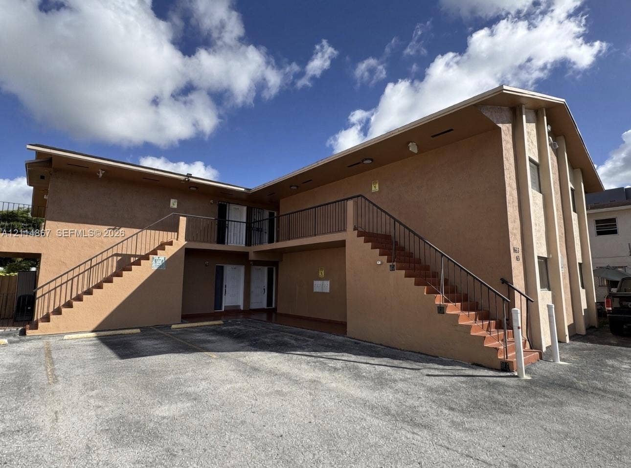 1663 W 41st Street, #1663, Hialeah, Hialeah, FL 33012 Two-story exterior featuring stucco siding, multiple external staircases with metal railings, a paved parking area, and recessed soffit lighting