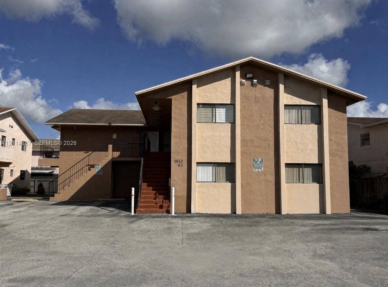 1663 W 41st Street, #1663, Hialeah, Hialeah, FL 33012 Multi-story exterior featuring a stucco facade, gable roofline, concrete parking area, and an external staircase with metal railing