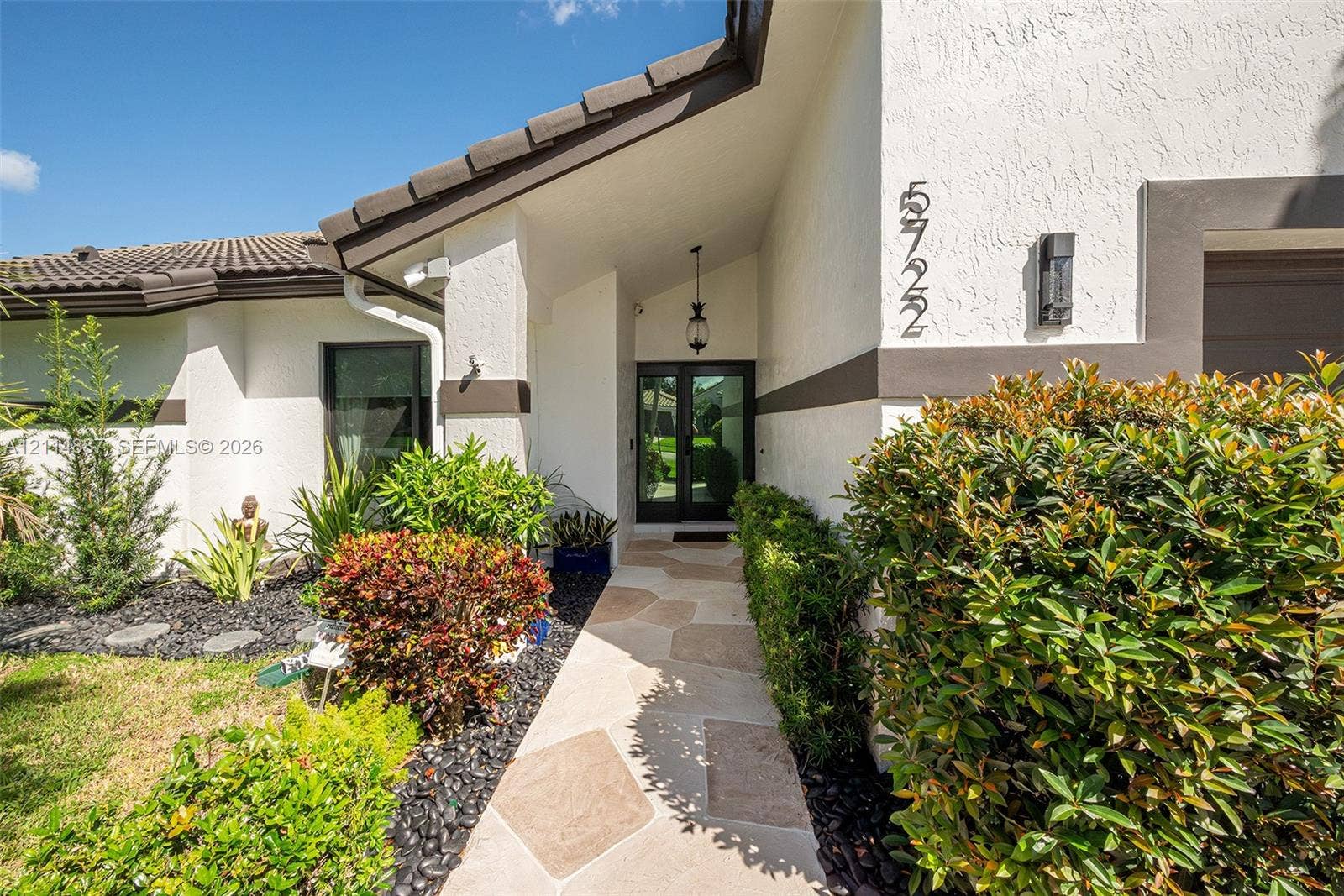 5722 Aspen Ridge Circle, Delray Beach, FL 33484 Stucco exterior featuring tile roofing, a paved stone walkway, and a glass-paneled entry door