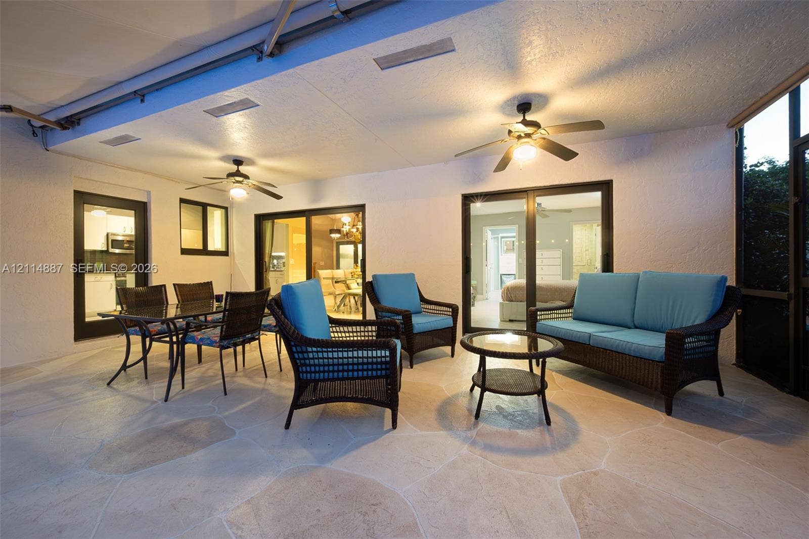 5722 Aspen Ridge Circle, Delray Beach, FL 33484 Covered patio featuring flagstone flooring, two ceiling fans, and multiple sliding glass door entries