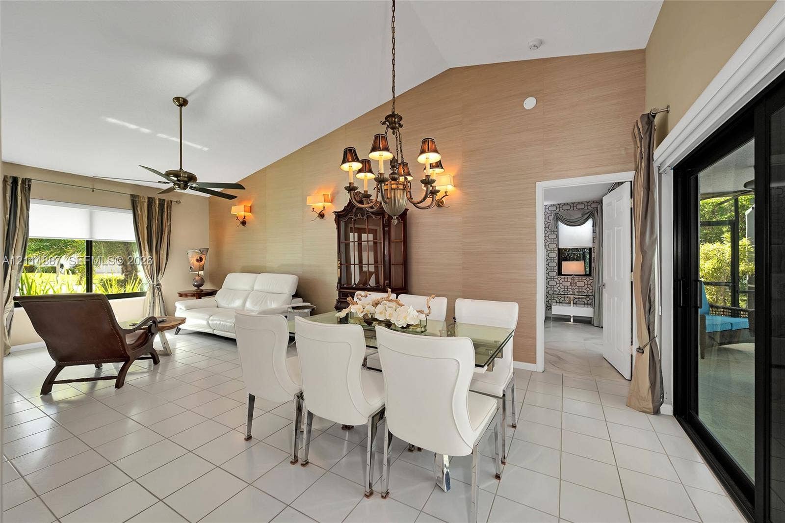 5722 Aspen Ridge Circle, Delray Beach, FL 33484 Vaulted ceilings, feature wall with textured surfacing, multi-arm chandelier, ceiling fan, and sliding glass doors with exterior access