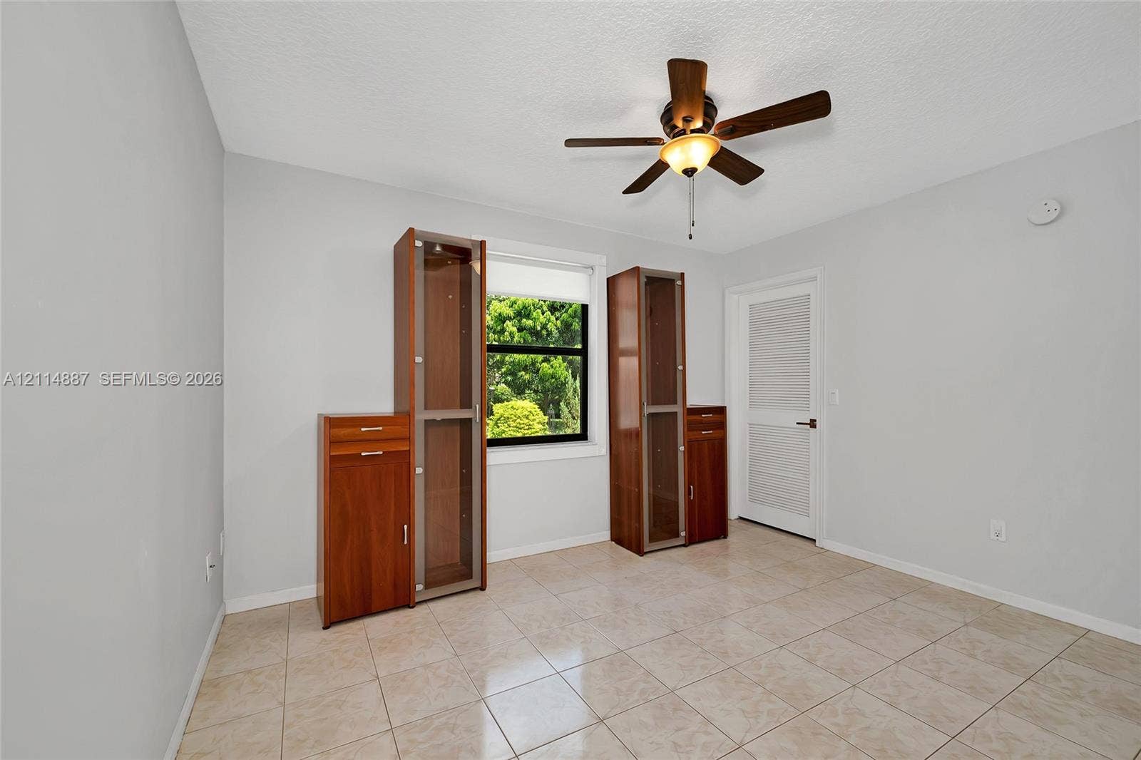 5722 Aspen Ridge Circle, Delray Beach, FL 33484 Room featuring neutral wall paint, tile flooring, built-in wooden cabinetry, a ceiling fan with integrated lighting, and a single-panel interior door