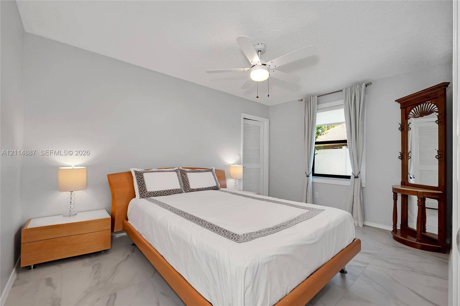 5722 Aspen Ridge Circle, Delray Beach, FL 33484 Neutral-toned room featuring large-format tile flooring, a white ceiling fan with integrated lighting, and a window with neutral drapery