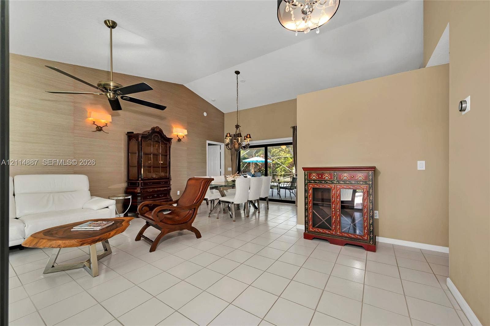 5722 Aspen Ridge Circle, Delray Beach, FL 33484 Vaulted ceilings, textured wall treatment, ceramic tile flooring, multi-arm chandelier, and sliding glass patio doors