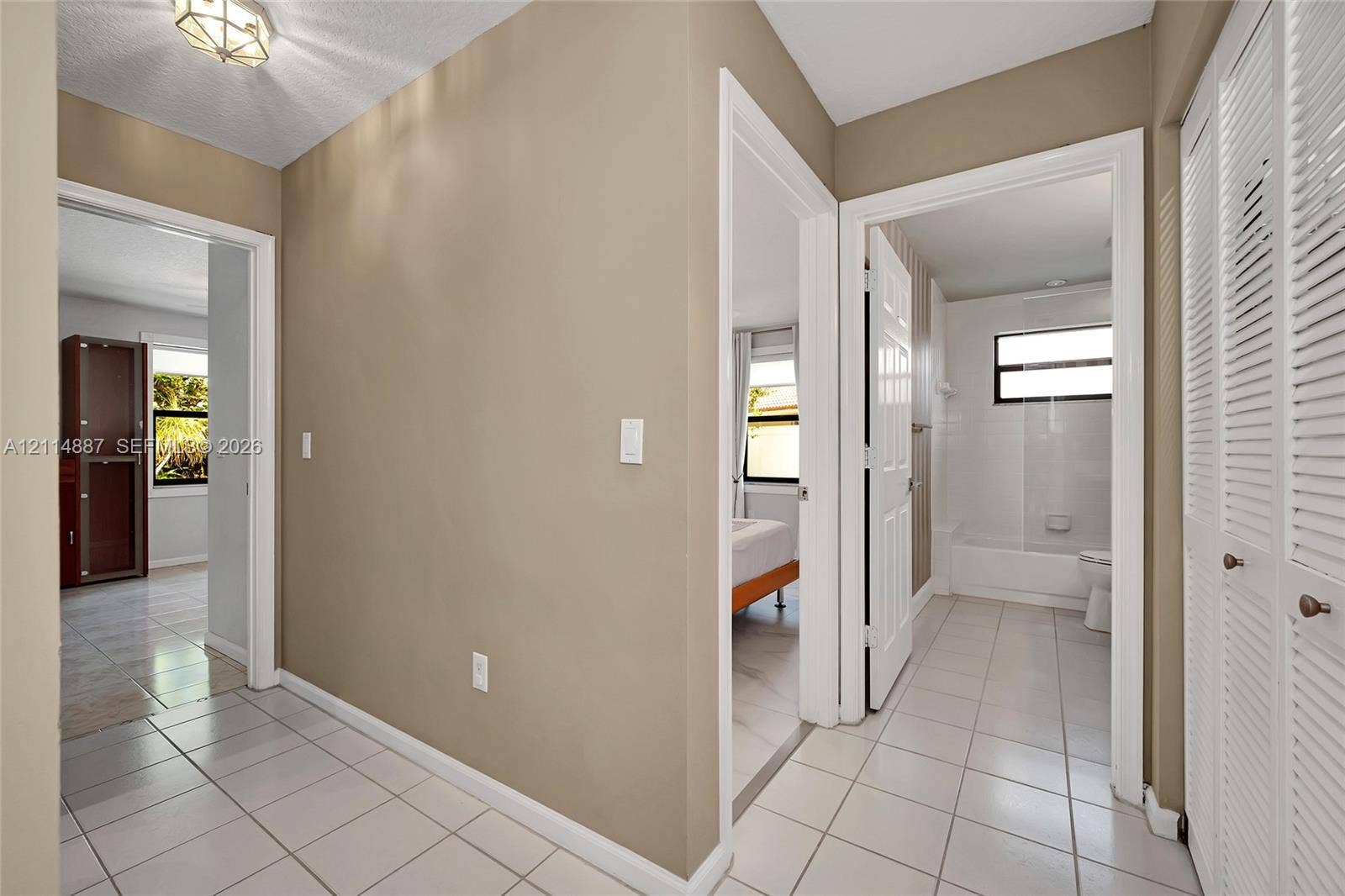 5722 Aspen Ridge Circle, Delray Beach, FL 33484 Neutral-toned hallway featuring ceramic tile flooring, recessed geometric lighting fixture, and floor-to-ceiling louvered closet doors