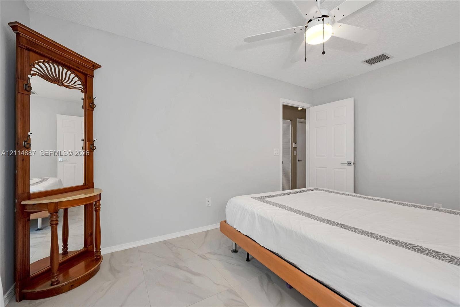 5722 Aspen Ridge Circle, Delray Beach, FL 33484 Neutral-toned interior space featuring light-colored stone-finish tile flooring, white-painted walls, and a ceiling-mounted fan with integrated lighting